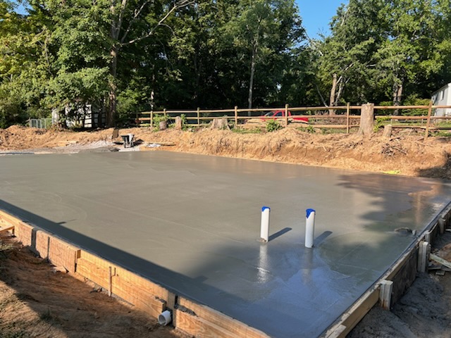 Finished large concrete slab with a smooth, level surface and plumbing rough-ins set